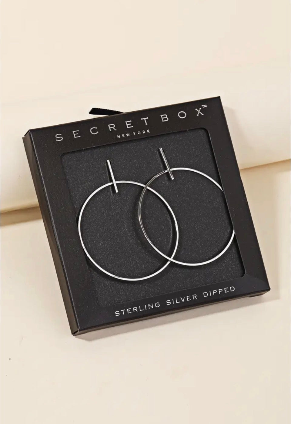 Sterling silver hoop earrings in a black square box by Secretbox New York, with 'STERLING SILVER DIPPED' printed on the front.